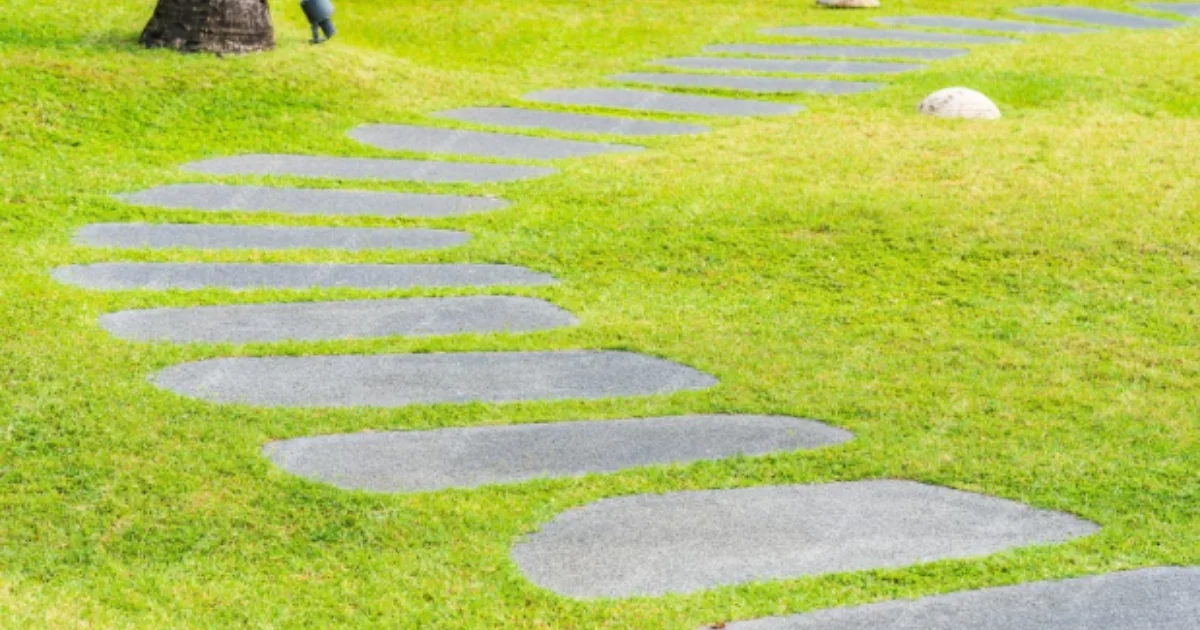Curved stone pathway set in bright green grass in a landscaped garden
